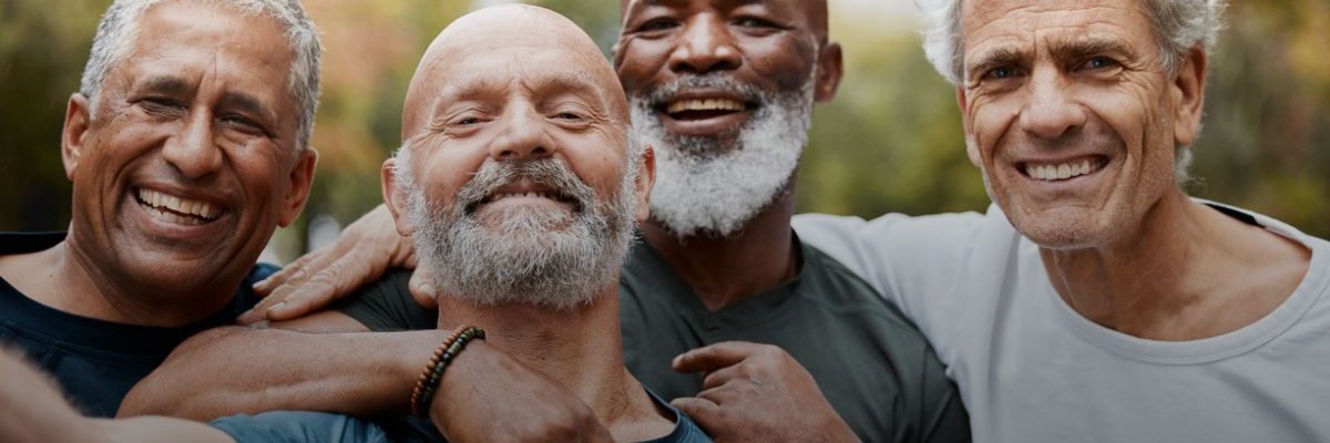 A group of four older men smiling and embracing each other outdoors, with an overlay text stating that one in ten men experience depression or anxiety, but less than half seek treatment. The quote is attributed to the Anxiety and Depression Association of America (ADAA)