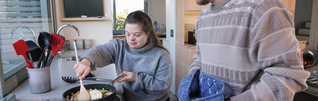 young woman with developmental disability cooks in her apartment where she receives supportive residential services