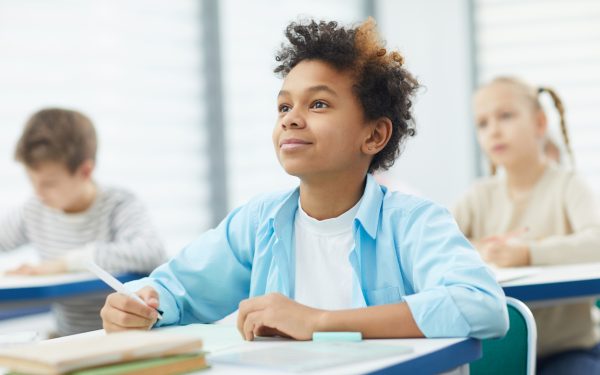a young boy sitting at a desk with a pen