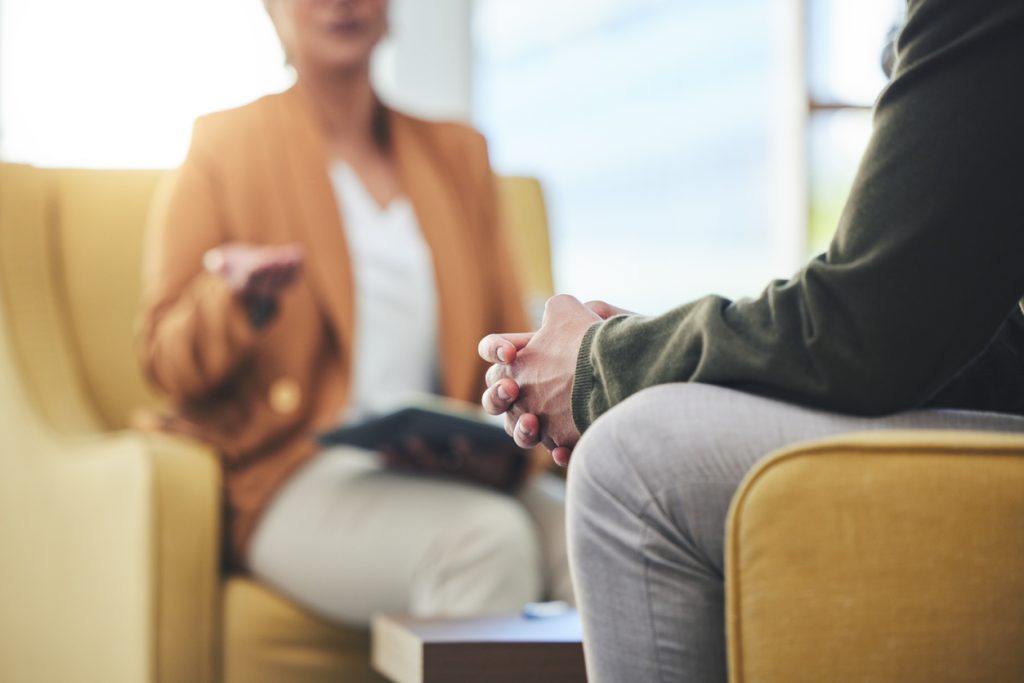 Two people sitting across from each other in a casual setting, offering support.