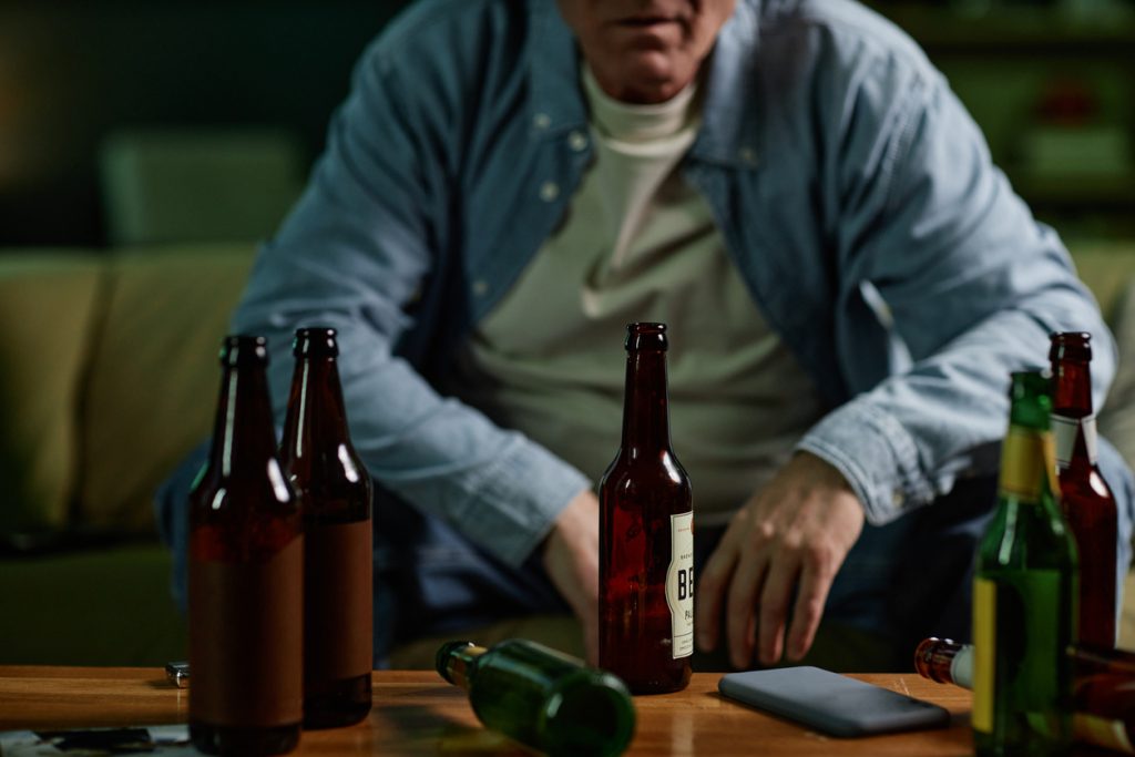 Man surrounded by empty beer bottles