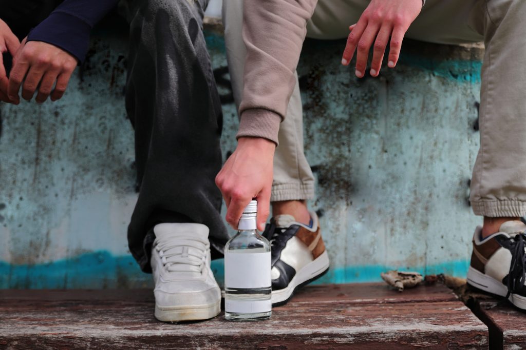 Two people sitting, bottle on ground