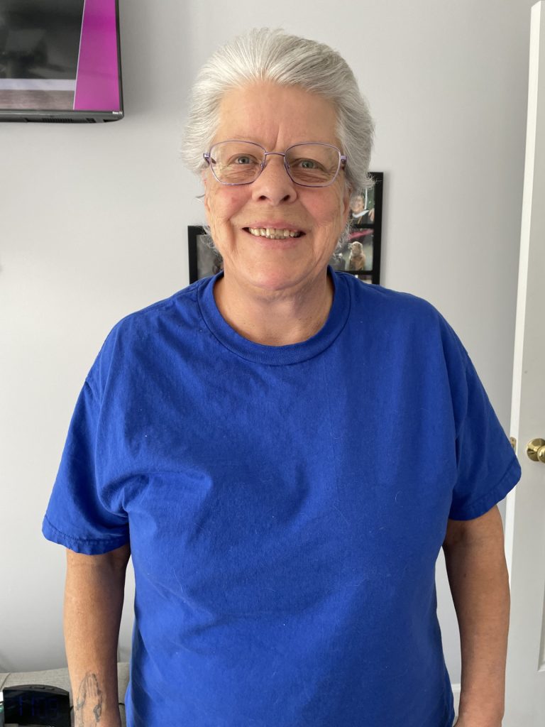 Person in blue shirt standing indoors smiling.

Laura during her behavioral health journey.