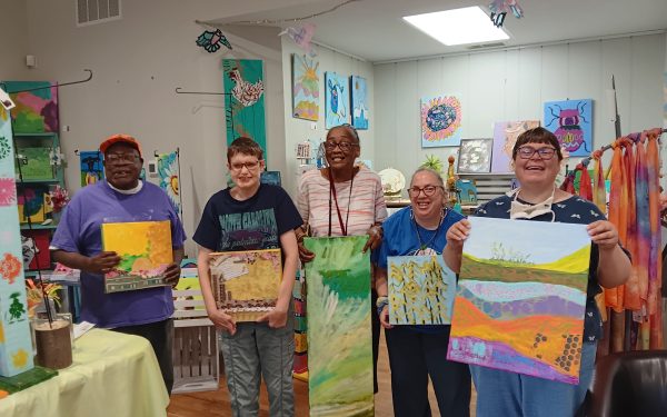 Group displaying colorful artwork indoors.