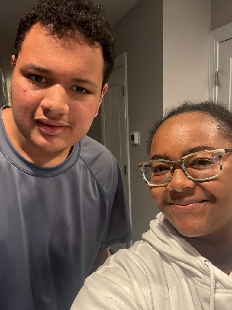 Two people smiling in a hallway.