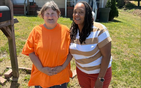 Two women smiling outside a house.