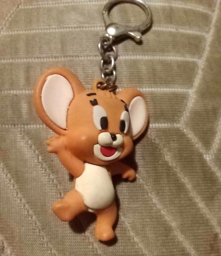 Small keychain of a smiling cartoon brown mouse.