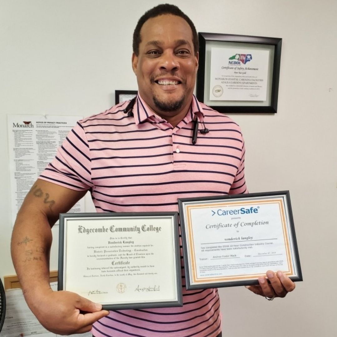 Vonderick Langley, resident of Azalea Gardens supervised living, holds his educational certificates wearing a red and white striped shirt.