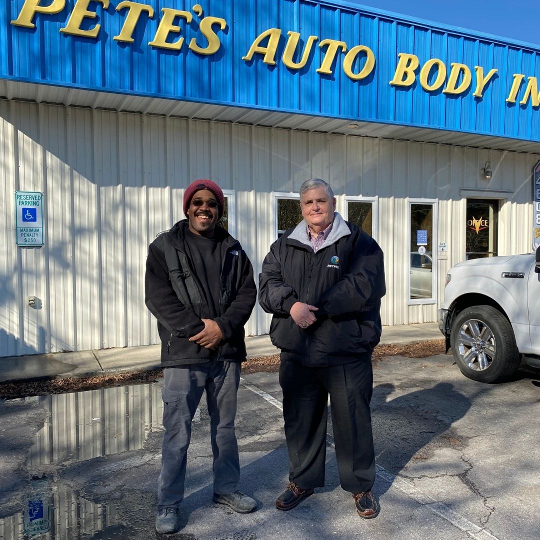 Person supported Brandon Blount stands next to Employment Peer Mentor Donald Winslow in front of Pete's Auto Body.