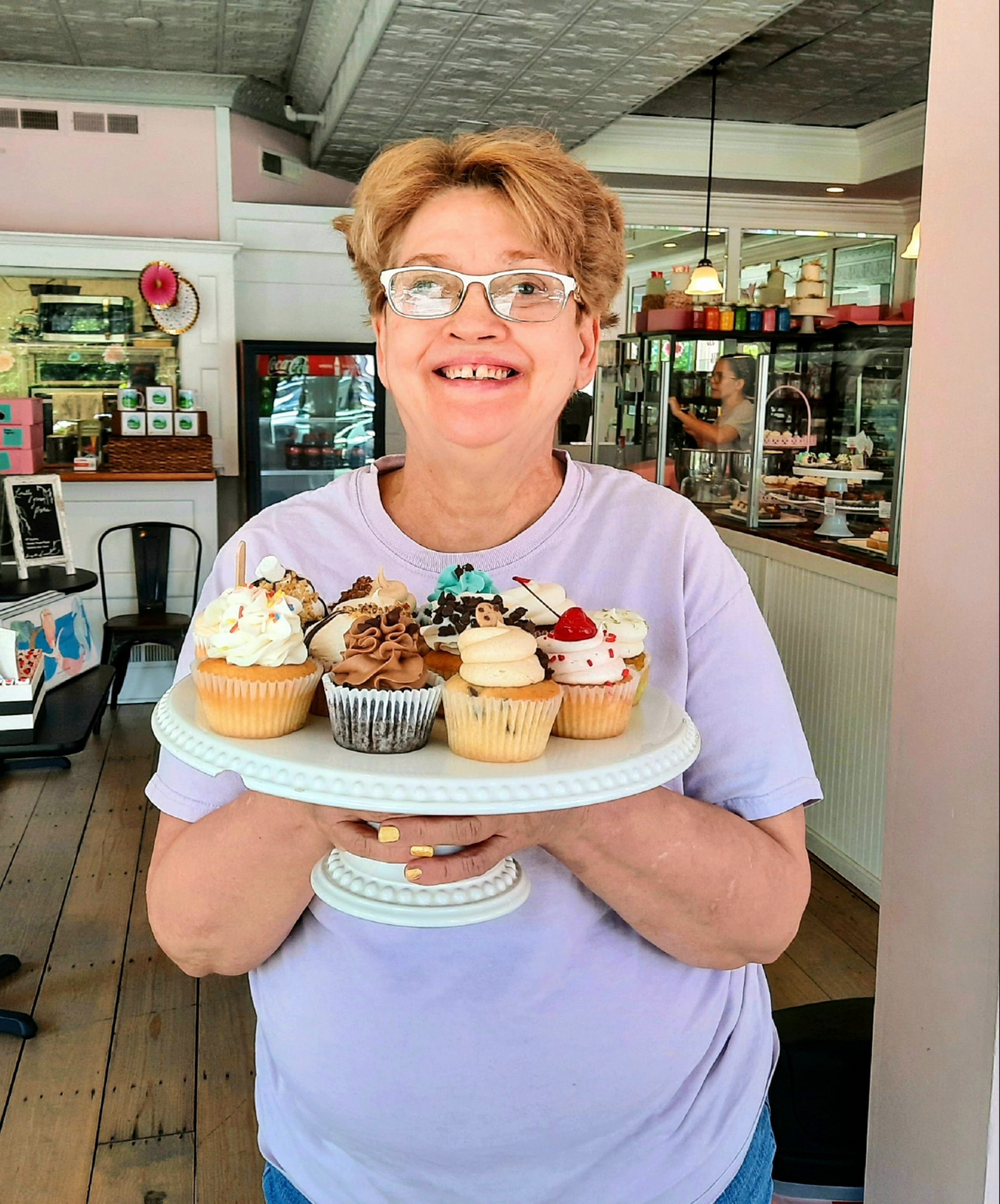 Linda Tyndall holds a display of colorful iced cupcakes at her job at C. Cupcakery in Moore County.