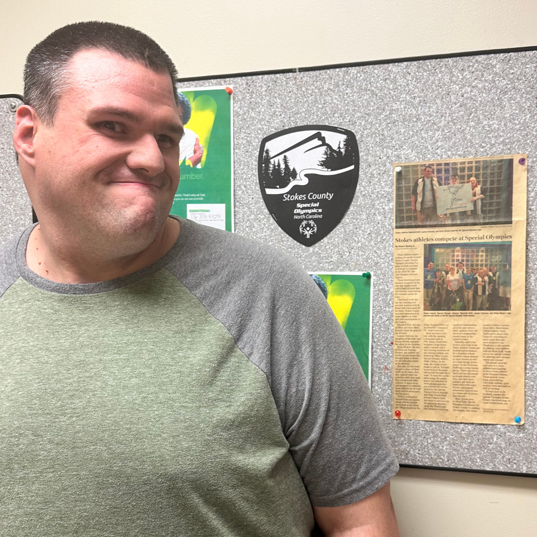 Ricky RIckert next to a Stokes County newspaper article written about his Special Olympics win. 